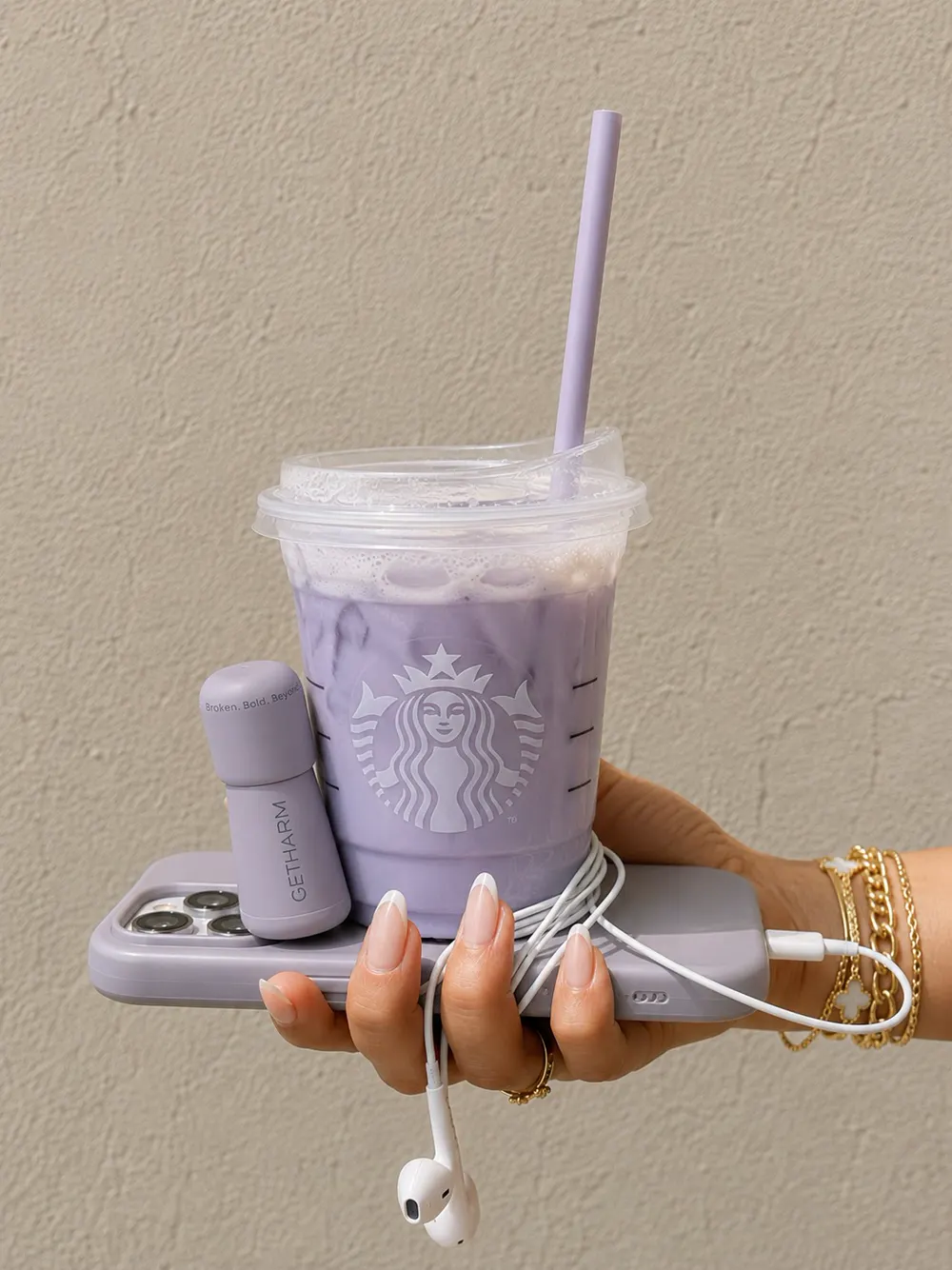 Hand holding a lavender iced drink, phone and MatteLip